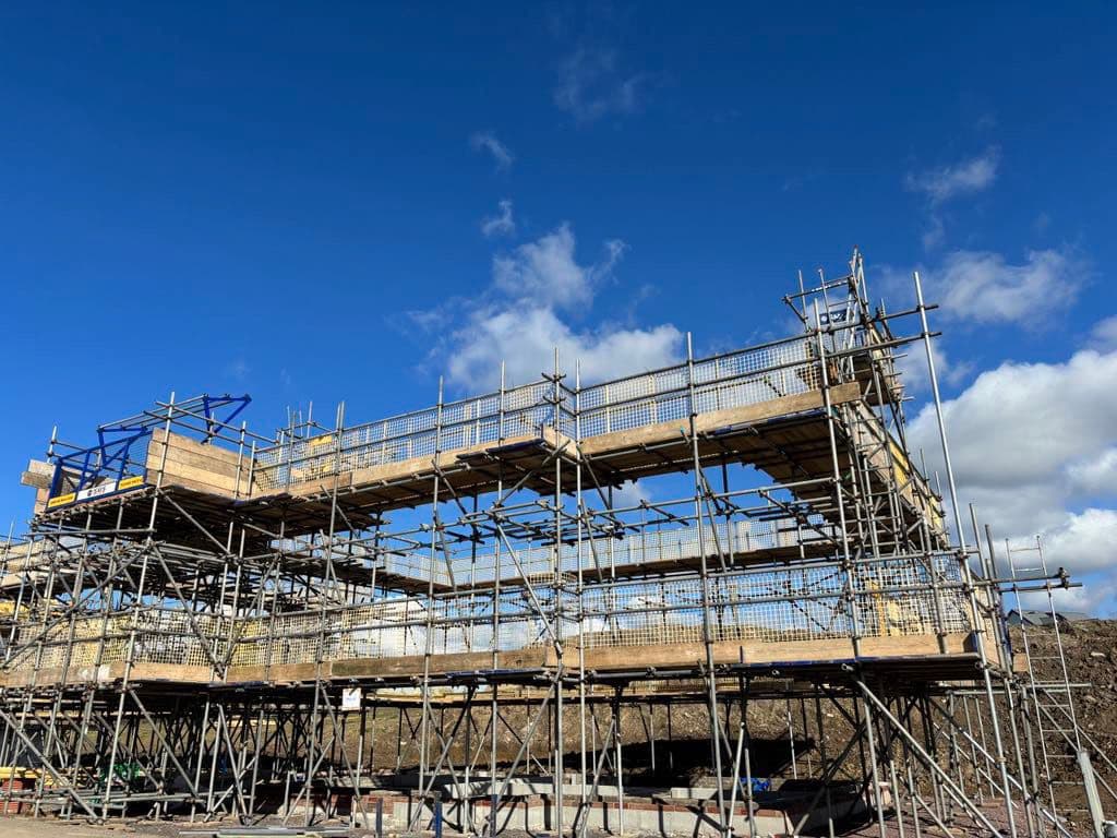 Commercial scaffolding set up outdoors in North Devon under a clear blue sky with some clouds.