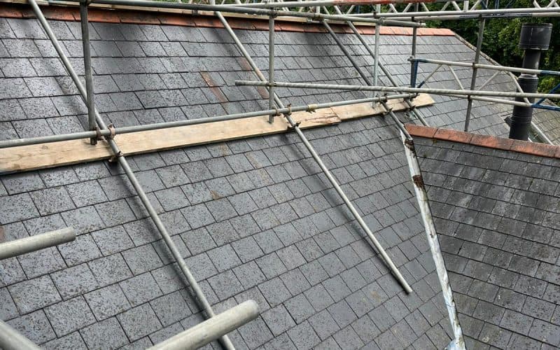 Domestic scaffolding set up around a slate tile roof during construction or maintenance work.